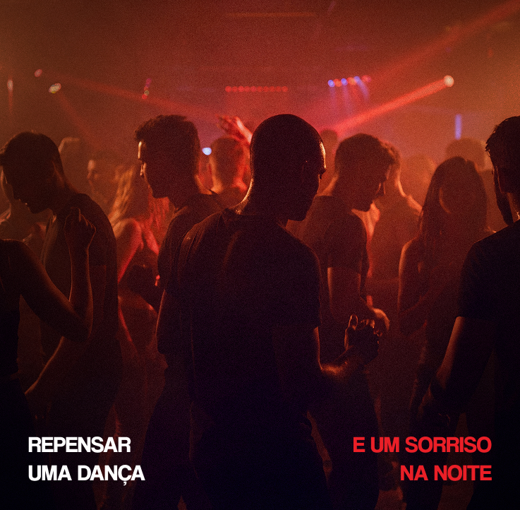 Pista de dança cheia, em contraluz vermelha: repensar uma dança e um sorriso na noite.
